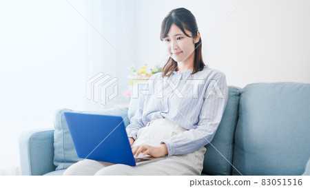Woman using a laptop on the sofa Woman using a laptop on the sofa 83051516