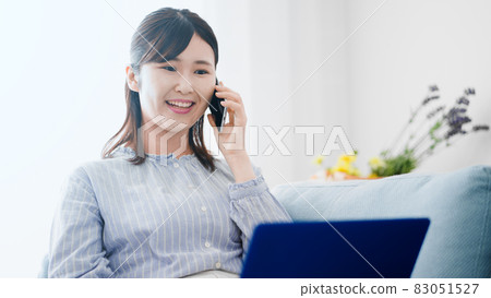A woman making a phone call while using a laptop A woman making a phone call while using a laptop 83051527