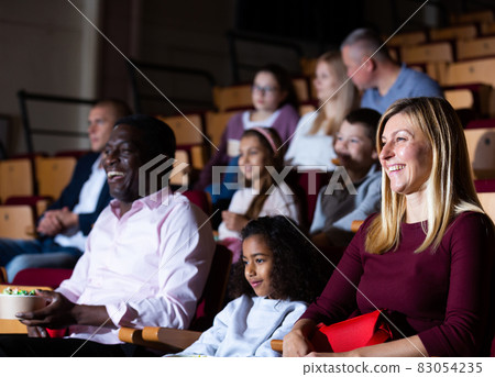 Laughing woman watching funny movie in cinema with family 83054235