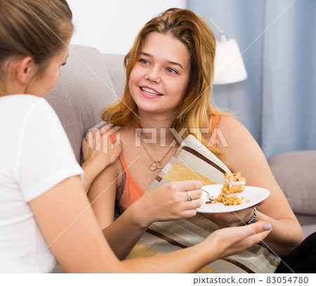 women on the sofa with plate of cake 83054780