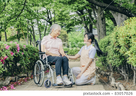 老年婦女和坐輪椅的女工作人員 老年婦女和坐輪椅的女工作人員 83057026