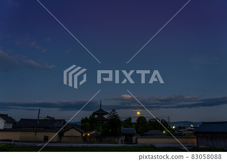 Ikaruga Town, Nara Prefecture, a harvest moon rising from the other side of the three-storied pagoda of Hokiji Temple, a World Heritage Site 83058088