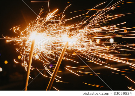 Bright glittering sparkler on blurred bokeh background Bright glittering sparkler on blurred bokeh background 83059824