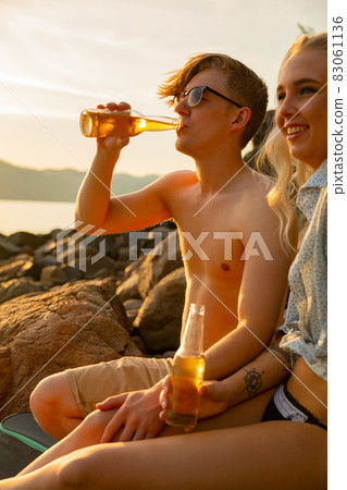 Man Drinking Beer By Smiling Girlfriend At Beach Man Drinking Beer By Smiling Girlfriend At Beach 83061136