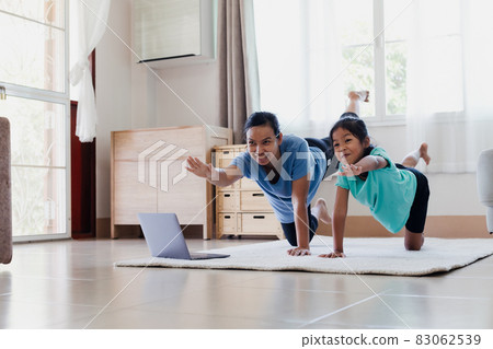 Asian young mother and her daughter doing stretching fitness exercise yoga together at home. Parent teaching child work out to be strong and maintain physical health and wellbeing in daily routine. 83062539