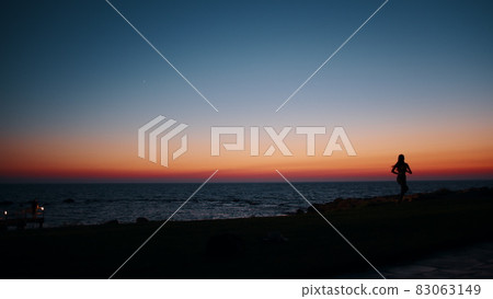 Silhouette of sporty young woman in activewear running along beach during evening time. Physical exercises during summer sunset over ocean. Motivation and endurance concept. 83063149