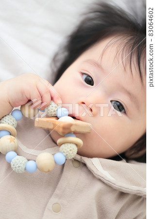6 month old baby girl biting a tooth-hardening toy 83064602