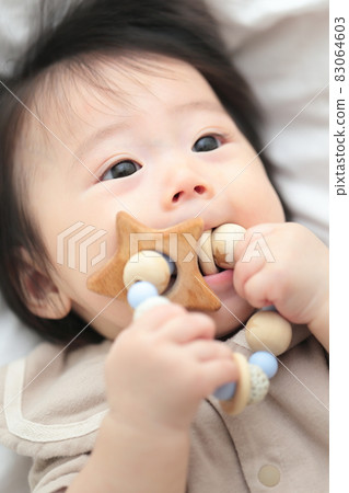 6 month old baby girl biting a tooth-hardening toy 83064603