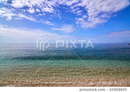 Tropical Asian beach with white sand, turquoise ocean against blue sky with clouds Tropical Asian beach with white sand, turquoise ocean against blue sky with clouds 83068605