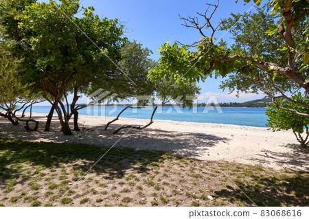 Tropical Asian beach with white sand, turquoise ocean against blue sky with clouds Tropical Asian beach with white sand, turquoise ocean against blue sky with clouds 83068616