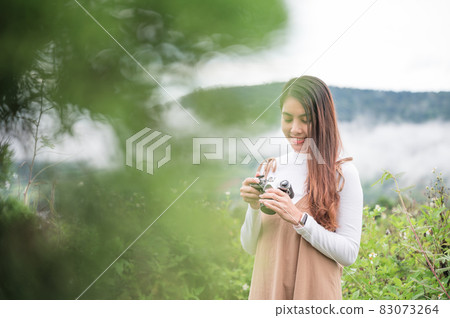 Young asian woman taking photo with retro film camera among the nature in the morning Young asian woman taking photo with retro film camera among the nature in the morning 83073264