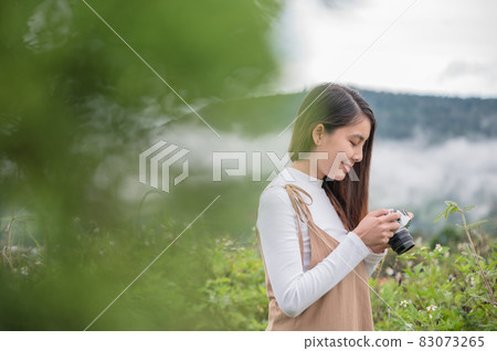 Young asian woman taking photo with retro film camera among the nature in the morning 83073265