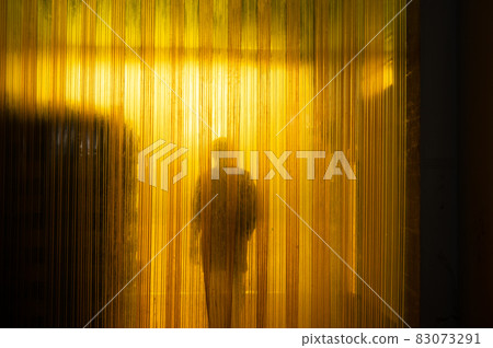 Yellow plastic curtain entrance with shadow of worker and cardboard package in warehouse Yellow plastic curtain entrance with shadow of worker and cardboard package in warehouse 83073291