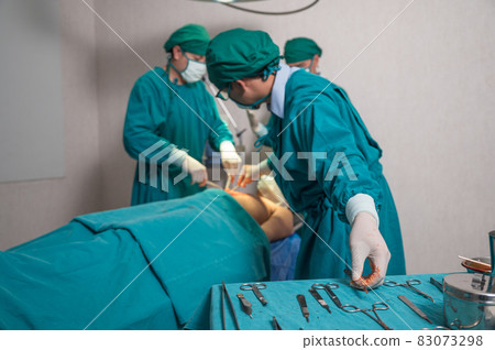 Surgeons team performing surgery a seriously injured patient and picking up medical equipment in operating room at hospital Surgeons team performing surgery a seriously injured patient and picking up medical equipment in operating room at hospital 83073298