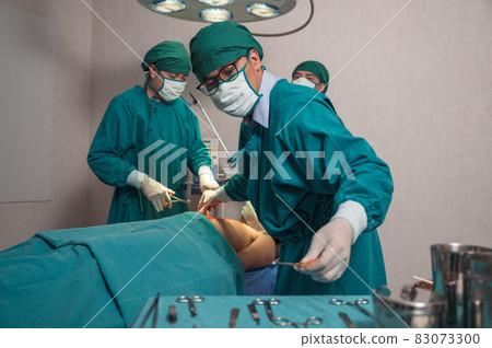 Surgeons team performing surgery a seriously injured patient and picking up medical equipment in operating room at hospital Surgeons team performing surgery a seriously injured patient and picking up medical equipment in operating room at hospital 83073300