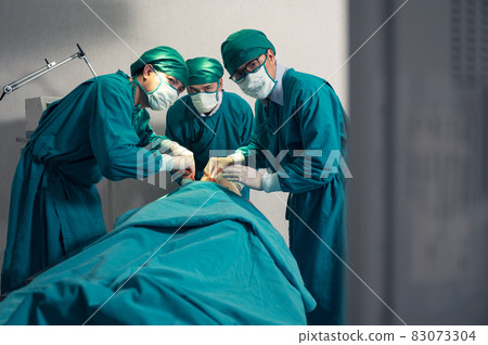 Team of surgeon in surgical gown operating accident patient and looking at monitor in operating room Team of surgeon in surgical gown operating accident patient and looking at monitor in operating room 83073304
