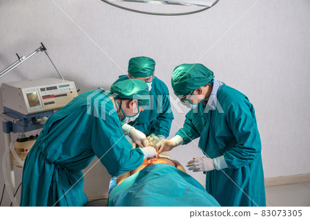 Surgeons team in surgical gown performing surgery a seriously injured patient in operating room at hospital Surgeons team in surgical gown performing surgery a seriously injured patient in operating room at hospital 83073305