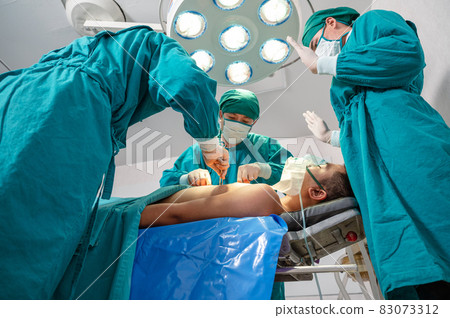 Surgeons team in surgical gown performing surgery a seriously injured patient in operating room 83073312