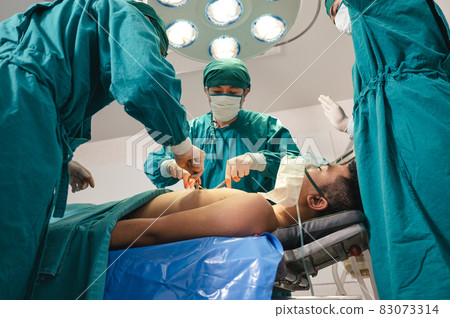 Surgeons team in surgical gown performing surgery a seriously injured patient in operating room at hospital 83073314