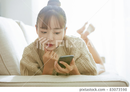 A young lady manipulating a smartphone on the sofa A young lady manipulating a smartphone on the sofa 83073598