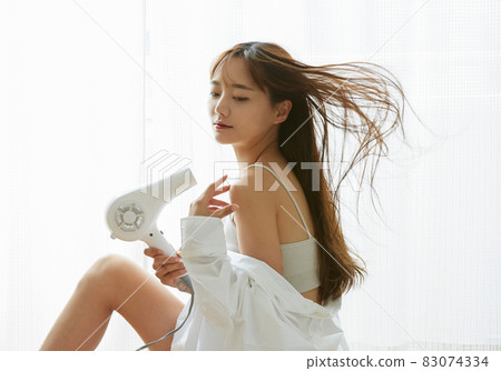 Young woman drying her hair 83074334