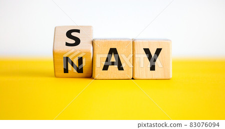 Say nay symbol. Turned a cube, changed the word 'say' to 'nay'. Beautiful yellow table, white background. Copy space. Business, motivation and say nay concept. 83076094