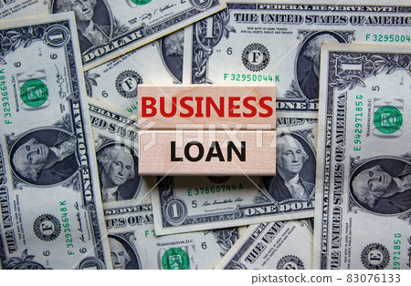 Time to business loan. Concept words 'business loan' on wooden blocks on a beautiful background from dollar bills. Business loan concept. Time to business loan. Concept words 'business loan' on wooden blocks on a beautiful background from dollar bills. Business loan concept. 83076133