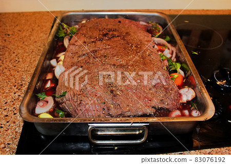 A moose brisket on a bed of vegetables in a roasting pan 83076192