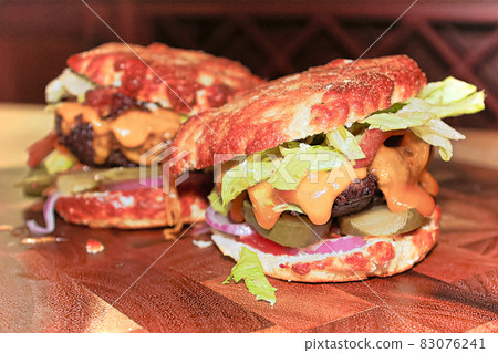 Closeup view of two messy keto burgers on a wooden board 83076241