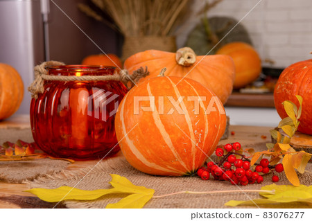 A pumpkin-shaped lamp is lit on a table decorated for Halloween. A pumpkin-shaped lamp is lit on a table decorated for Halloween. 83076277