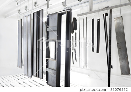 Factory metal surface coating paint in painting chamber. Powder coating of metal parts in spray booth. Coating industry painting metal products in paint booth. Steel parts Inside industry paint garage 83076352