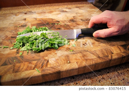 Closeup of a hand holding a knife cutting green mint Closeup of a hand holding a knife cutting green mint 83076415