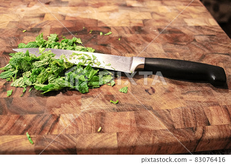 Closeup of a knife on a cutting board with fresh green mint 83076416