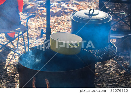 Two pots sitting on grill over a campfire Two pots sitting on grill over a campfire 83076510