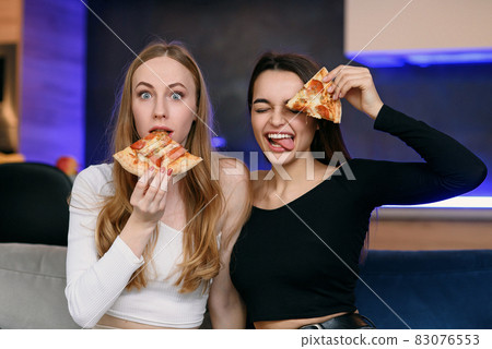 Two women having fun at home, opening pizza box, food delivery, home party 83076553