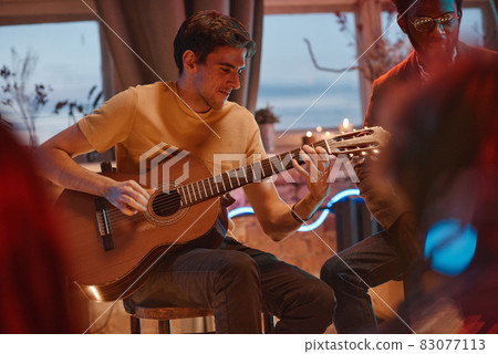 Man playing guitar for his friends Man playing guitar for his friends 83077113