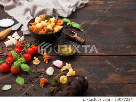 Trottole pasta in black bowl with parmesan cheese and tomatoes, basil with garlic and oil Trottole pasta in black bowl with parmesan cheese and tomatoes, basil with garlic and oil 83077224