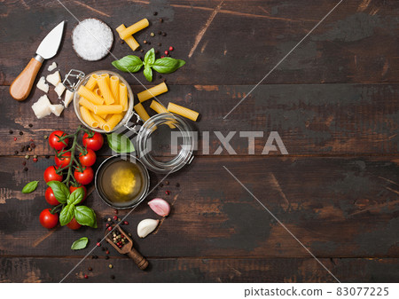 Fresh raw penne pasta in glass jar with tomatoes and basil, garlic and oil with parmesan cheese  83077225