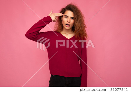 Portrait of young emotional beautiful brunette curly woman with sincere emotions wearing trendy pink 83077241