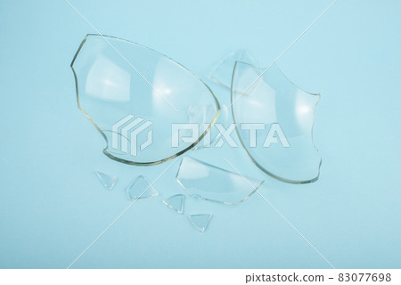 Broken glass pieces on pastel blue background. Close up, top view. Broken glass pieces on pastel blue background. Close up, top view. 83077698