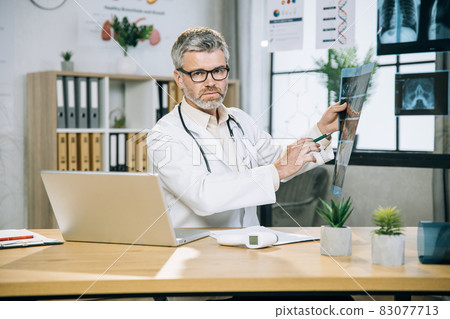 Competent mature therapist analysing results of x ray scan Competent mature therapist analysing results of x ray scan 83077713