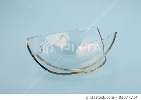 Broken glass pieces on pastel blue background. Broken glass pieces on pastel blue background. 83077714