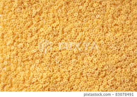 Macaroni stars texture. Italian stelline pasta for soup. Yellow small star-shaped uncooked noodles. High-quality photo Macaroni stars texture. Italian stelline pasta for soup. Yellow small star-shaped uncooked noodles. High-quality photo 83078491
