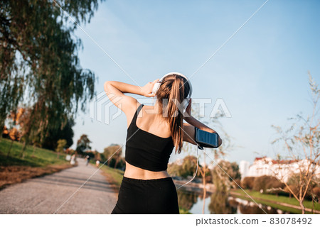 A girl in headphones is engaged in outdoor fitness in a metropolis. running and sports in summer A girl in headphones is engaged in outdoor fitness in a metropolis. running and sports in summer 83078492