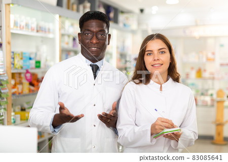 Portrait of two positive pharmacists in a pharmacy, making notes 83085641