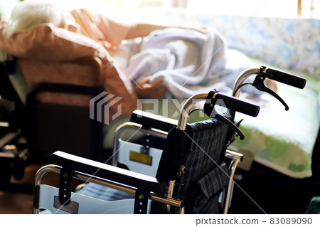 斜倚在護理床上的老年婦女和輪椅 83089090