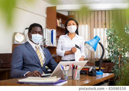 Two business colleagues in protective masks in office interior Two business colleagues in protective masks in office interior 83090338