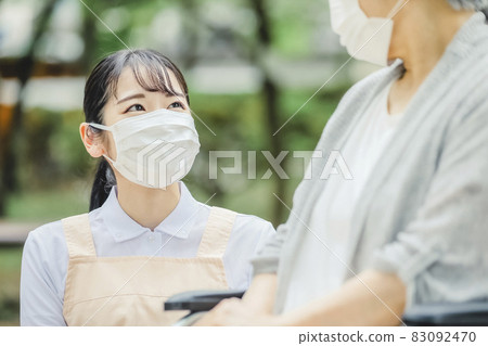 Elderly women in wheelchairs and female staff (masks) Elderly women in wheelchairs and female staff (masks) 83092470