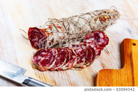 Piacenza salami cut in slices on a wooden surface, close-up 83094342