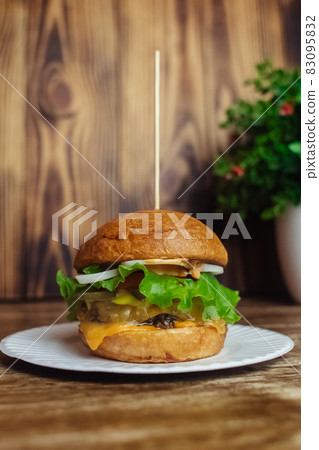 Close-up of a standard burger. Adult fast food in a restaurant or cafe. Macro photo of burger ingredients with meat, cheese and herbs. Eco burgers for the whole family 83095832